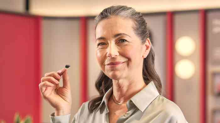 Femme tenant un appareil auditif dans sa main