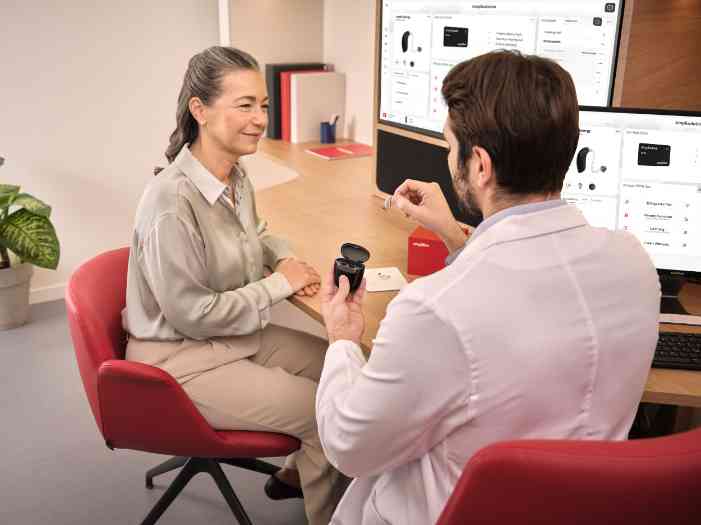 Un audioprothésiste montre un appareil auditif à un client.