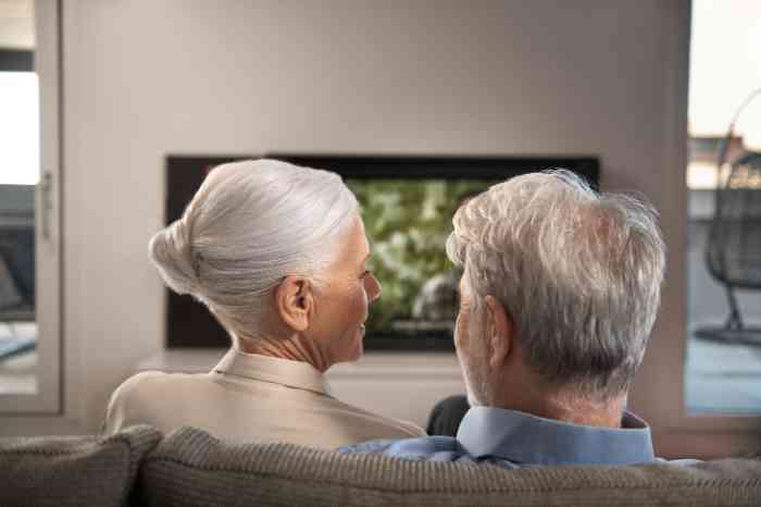 elderly couple sitting on a sofa, looking at each other.