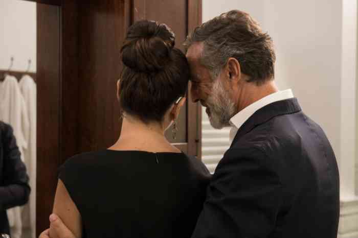 A couple is ready for a night out. She's elegantly wearing ahearing aid