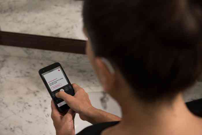 A woman is checking her hearing aid's app from her smartphone
