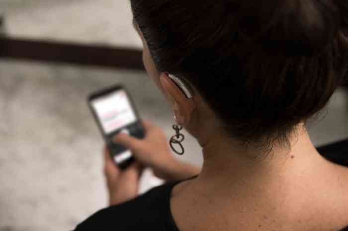 woman wearing hearing aids using a smartphone app related to a service.