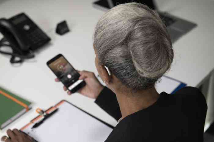 Entrepreneur with a hearing aid checking an app on her phone