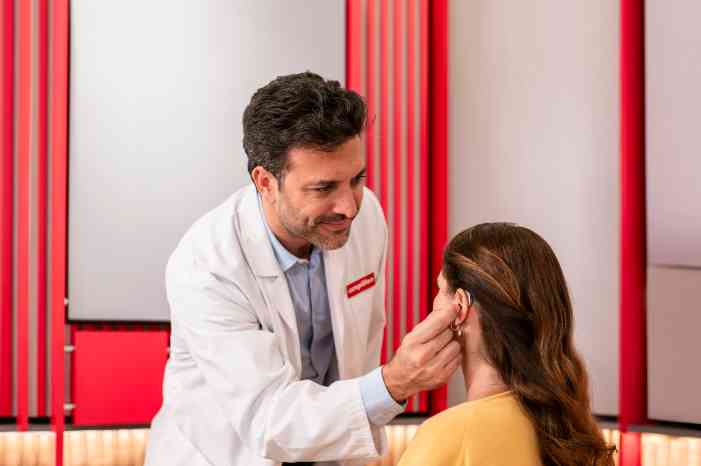 Audioprothésiste adaptant un appareil auditif à l’oreille gauche du client