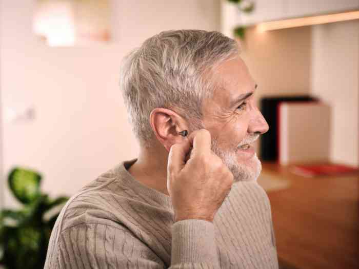 Homme de profil s'apprêtant à porter un appareil auditif 