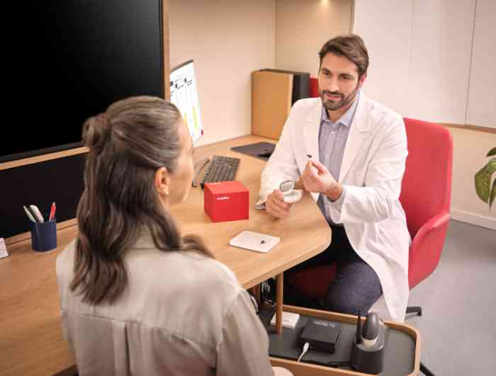 audiologist showing ampli mini while wearing a coat.