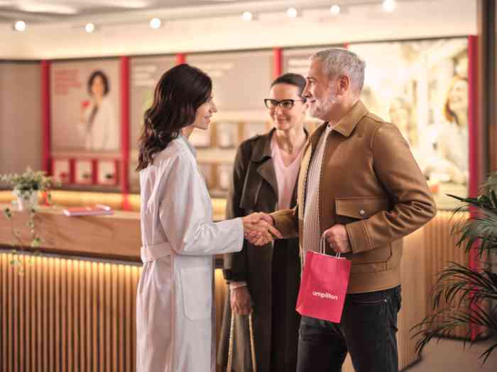 couple saluant l'audiologiste en blouse dans un magasin Amplifon.