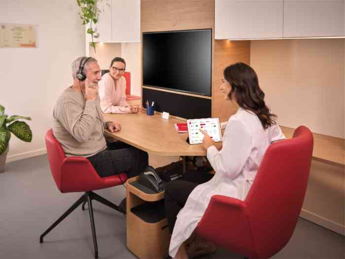 un couple faisant un test auditif avec un Otopad avec un audiologiste en blouse.