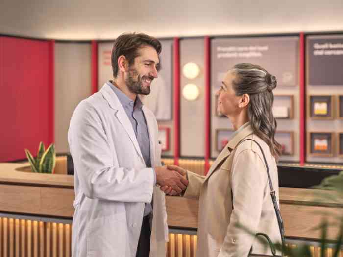 audiologist in a lab coat welcoming a woman.
