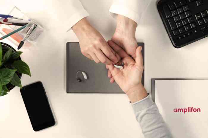 An hearing care professional handing an hearing aid to a customer
