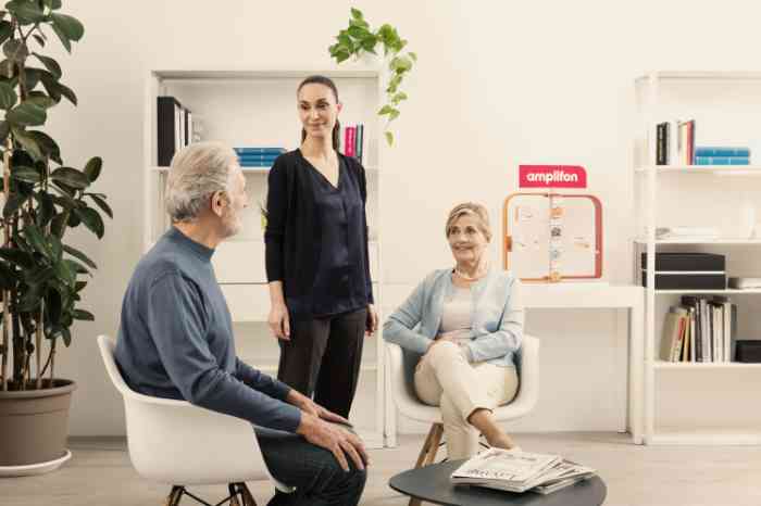Audiologist standing and talking with two seated clients in an Amplifon store.