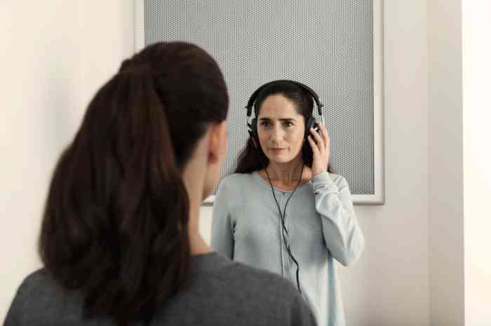 A woman with her left hand resting on the headphones during a hearing test