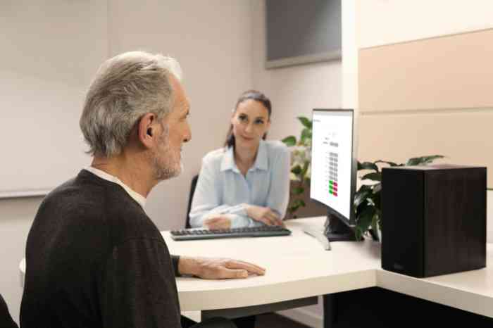 An elderly man with an Amplifon professional performing a hearing test.