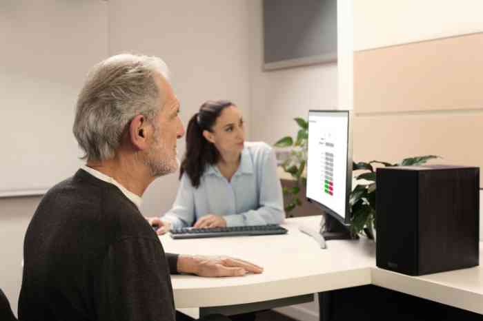 An elderly man with an Amplifon professional performing a hearing test.