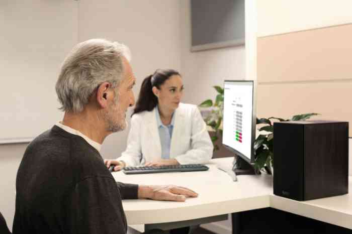 An elderly man with an Amplifon professional performing a hearing test.