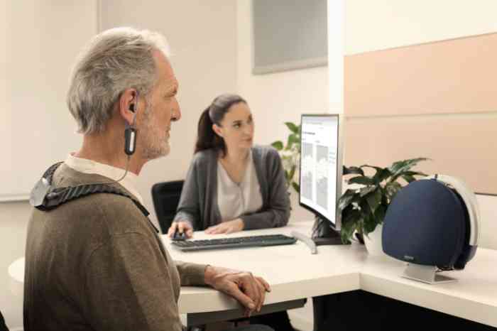 A man wearing a hearing test device while an Amplifon professional analyzes the results.