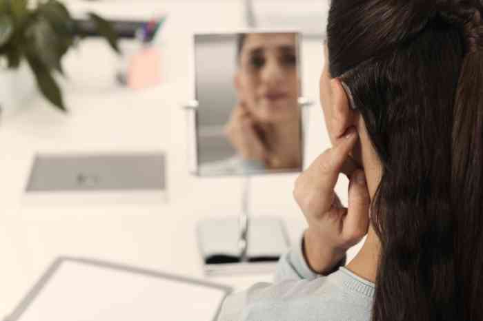 A woman looking at herself in the mirror with a focus on the BTE hearing aid.