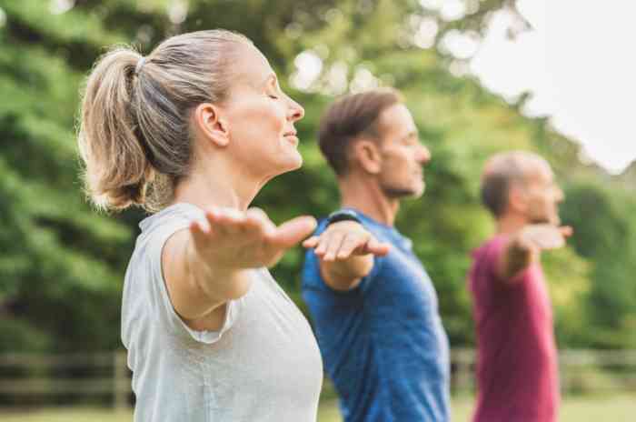 three people practicing yoga outdoors.
