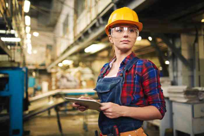 femme travaillant en usine avec un casque de protection.