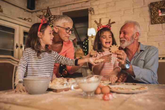 grandparents and two grandchildren making christmas cookies.