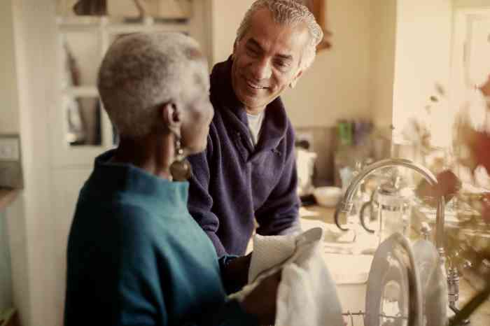couple smiling while washing dishes.