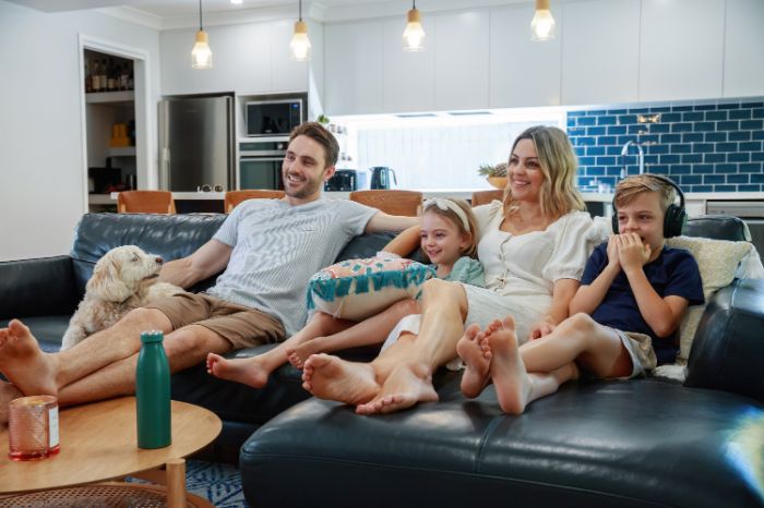 Famille sur le canapé dans la cuisine regardant la télévision