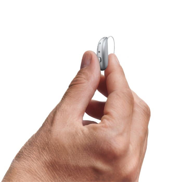 Une femme qui met une boucle d'oreille et porte un appareil auditif