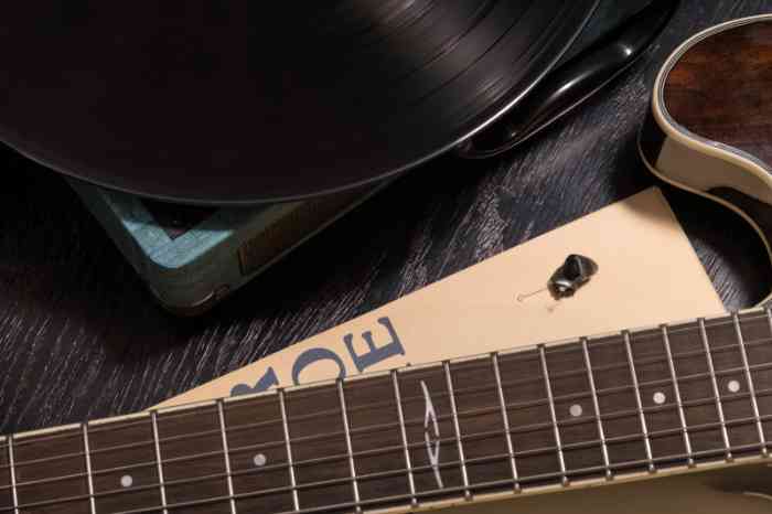 An in-the-ear hearing aid, a guitar and a vinyl