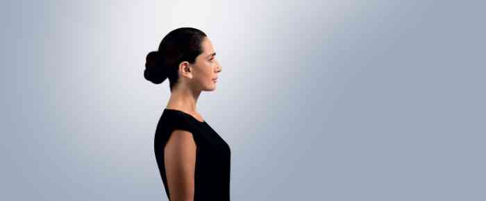 Profile of a woman with a bun and black shirt wearing an Amplifon ITE hearing aid.